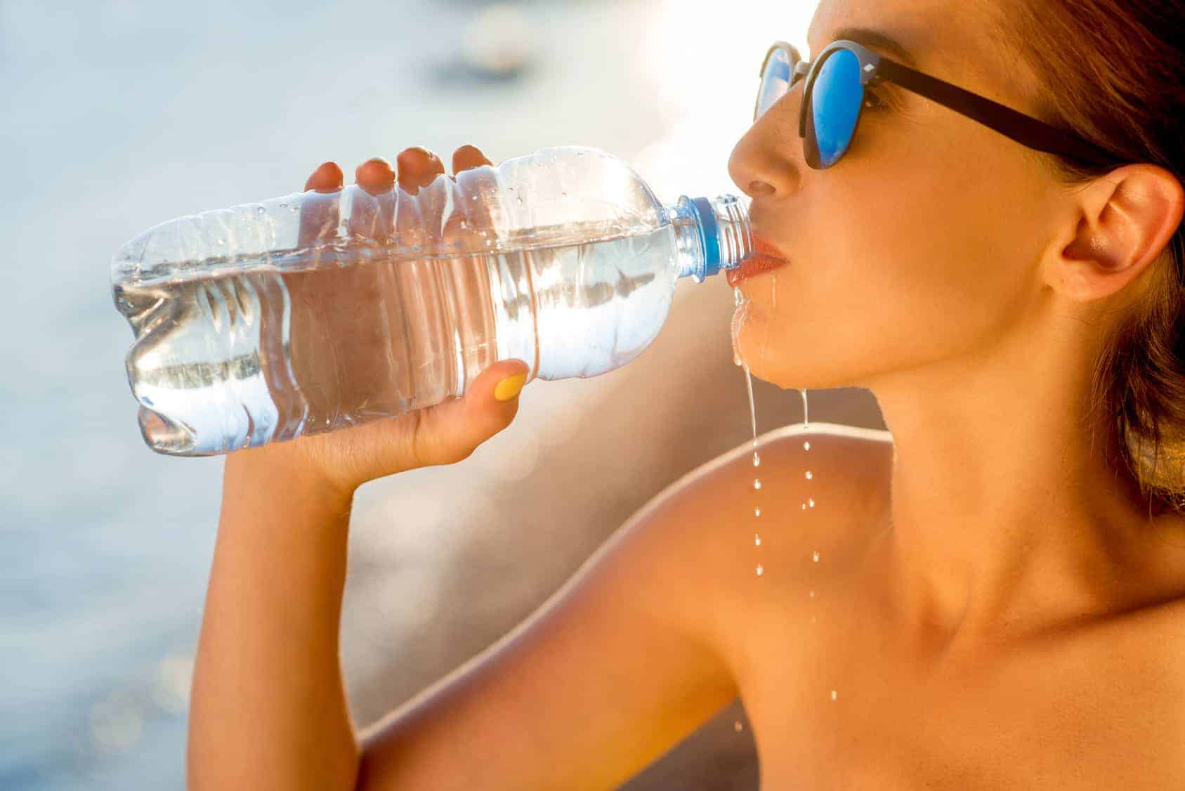 woman drinking from plastic bottle